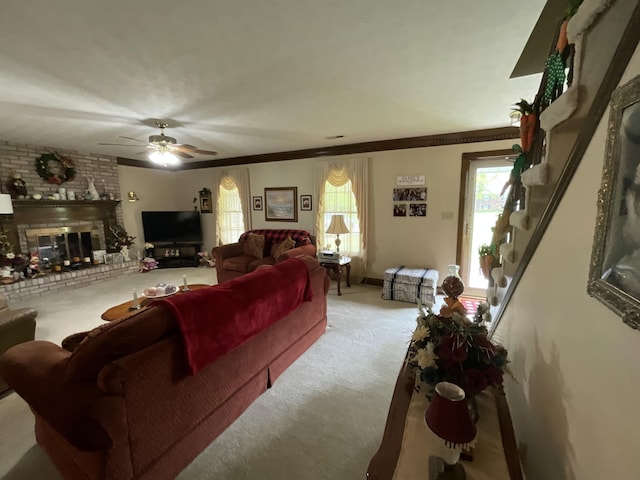carpeted living room featuring a brick fireplace, ceiling fan, and crown molding