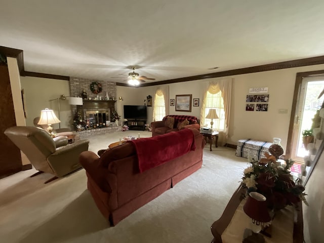 living room featuring ceiling fan, a brick fireplace, ornamental molding, and light colored carpet