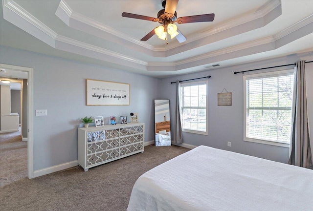 carpeted bedroom featuring a ceiling fan, visible vents, a raised ceiling, baseboards, and ornamental molding