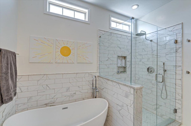 bathroom featuring tile walls, a soaking tub, and a stall shower
