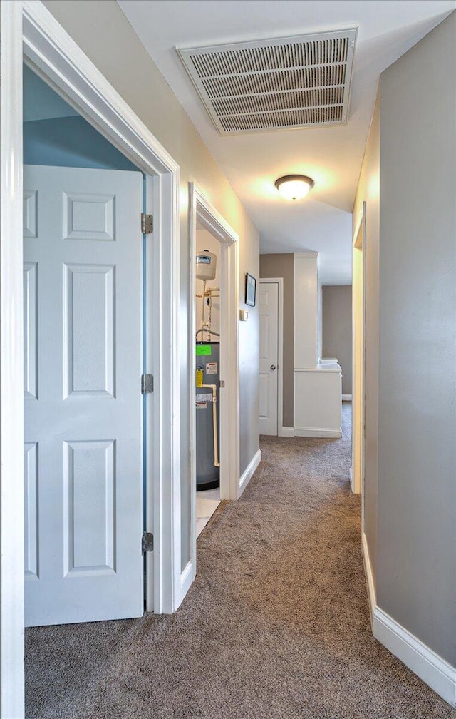 hall featuring water heater, baseboards, carpet, and visible vents