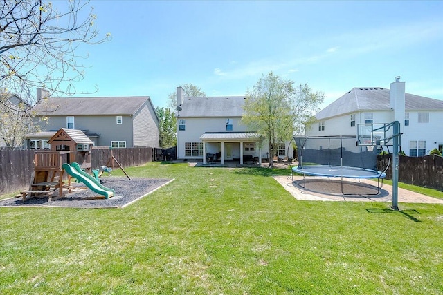 back of house featuring a lawn, a fenced backyard, a trampoline, and a playground
