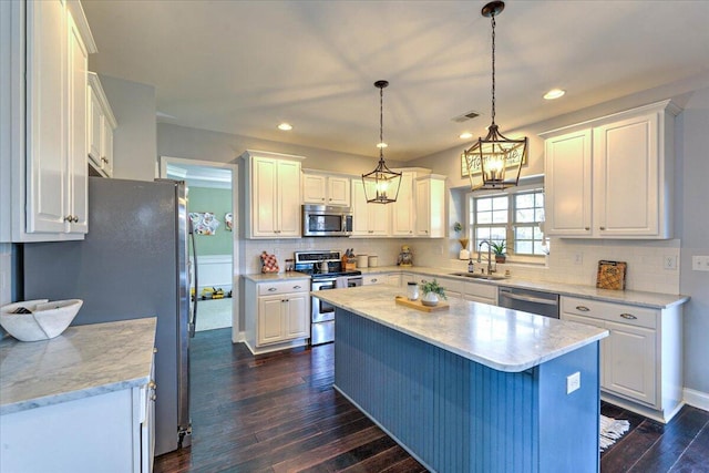 kitchen featuring a kitchen island, dark wood-style floors, white cabinetry, a sink, and appliances with stainless steel finishes