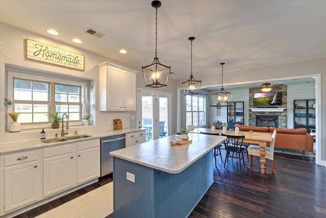 kitchen with a sink, dishwasher, a center island, dark wood-type flooring, and visible vents