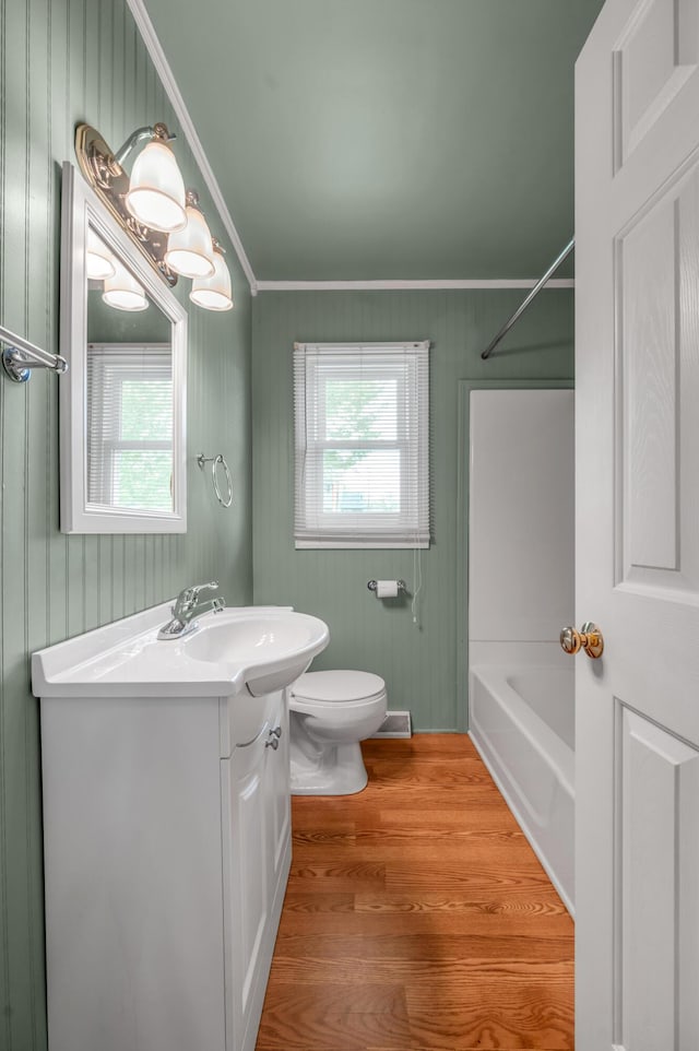 full bathroom featuring ornamental molding, toilet, a wealth of natural light, and wood finished floors