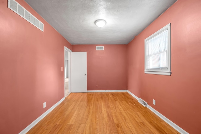 empty room with visible vents, baseboards, and light wood-style floors