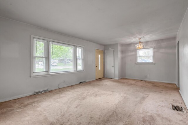 carpeted spare room with an inviting chandelier, visible vents, and baseboards