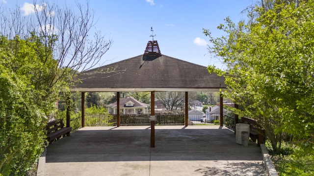 view of home's community with fence, a carport, driveway, and a gazebo