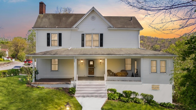 farmhouse-style home with a lawn, a chimney, and a porch