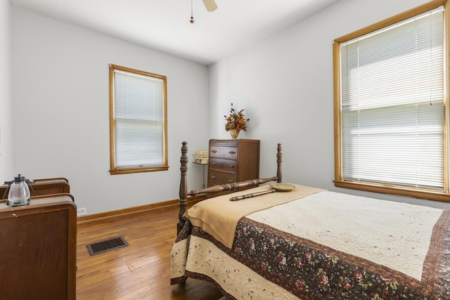 bedroom with baseboards, visible vents, wood finished floors, and a ceiling fan