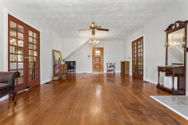 unfurnished living room with french doors, baseboards, ceiling fan with notable chandelier, and wood-type flooring