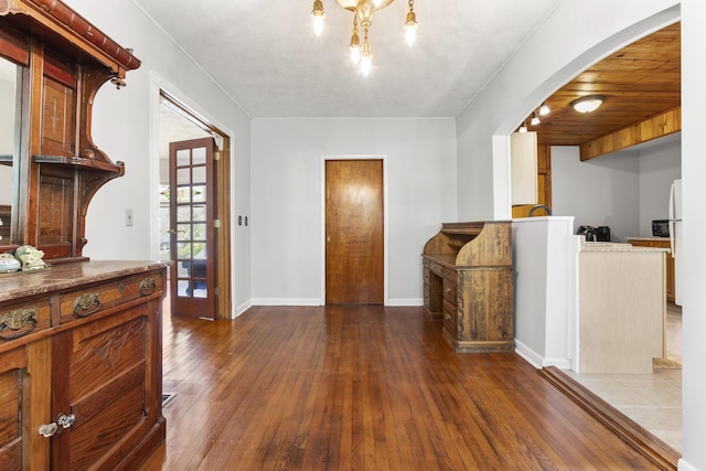 interior space featuring baseboards, arched walkways, a notable chandelier, and hardwood / wood-style flooring