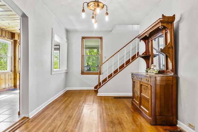 entrance foyer with an inviting chandelier, stairs, hardwood / wood-style flooring, baseboards, and visible vents