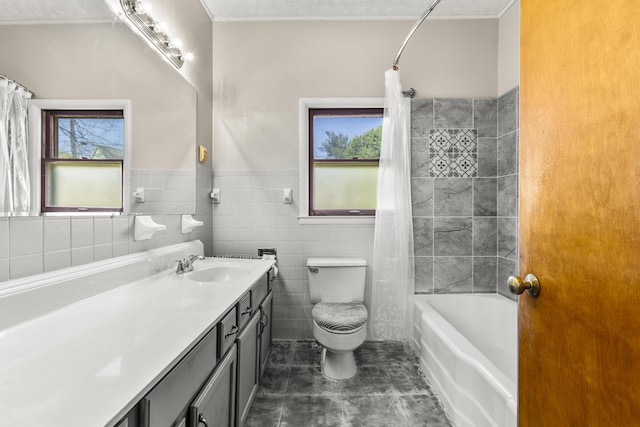 bathroom with a wainscoted wall, toilet, tile walls, shower / bathtub combination with curtain, and vanity