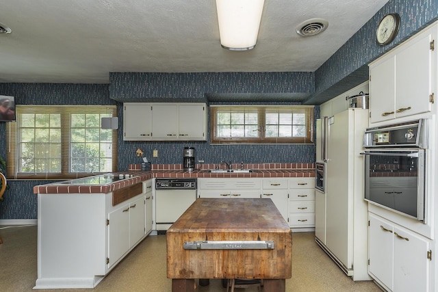 1964 Shadybrook Ln, Lexington, KY 40502 - kitchen with white appliances, wallpapered walls, a sink, a peninsula, and white cabinetry