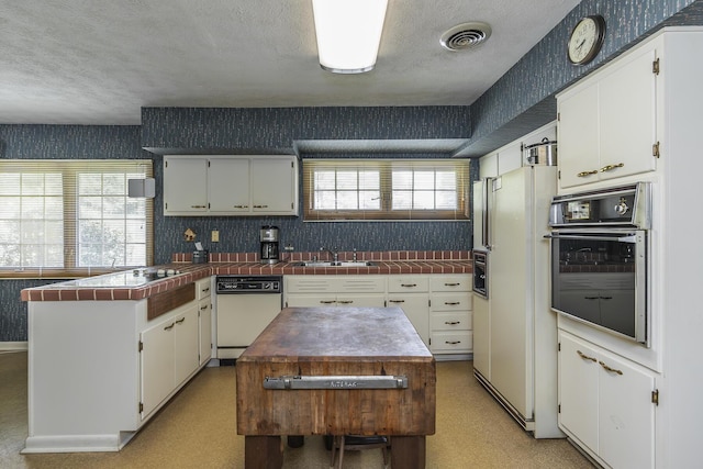 1964 Shadybrook Ln, Lexington, KY 40502 - kitchen with white appliances, wallpapered walls, a peninsula, white cabinets, and tile counters
