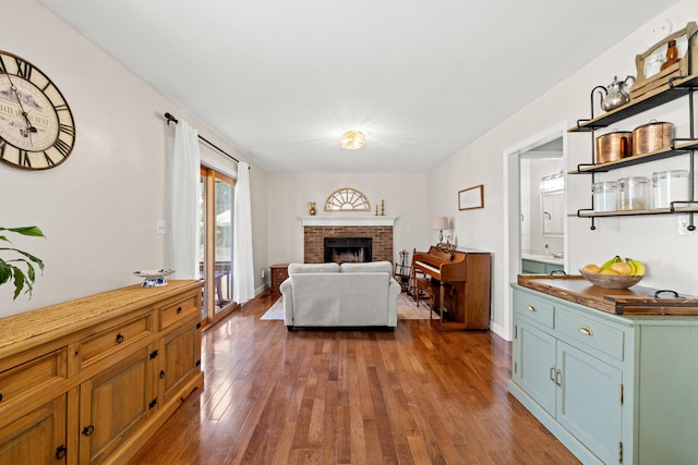 living room featuring baseboards, a brick fireplace, and dark wood-style floors