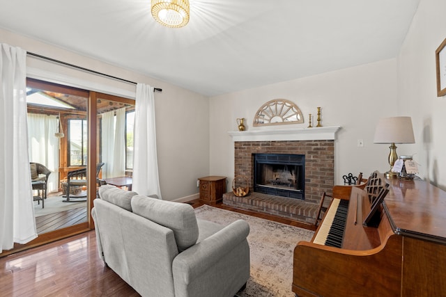 living room with a brick fireplace and wood finished floors
