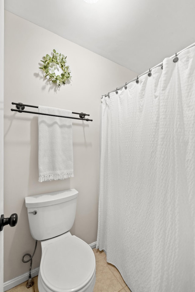 bathroom featuring baseboards, tile patterned floors, and toilet