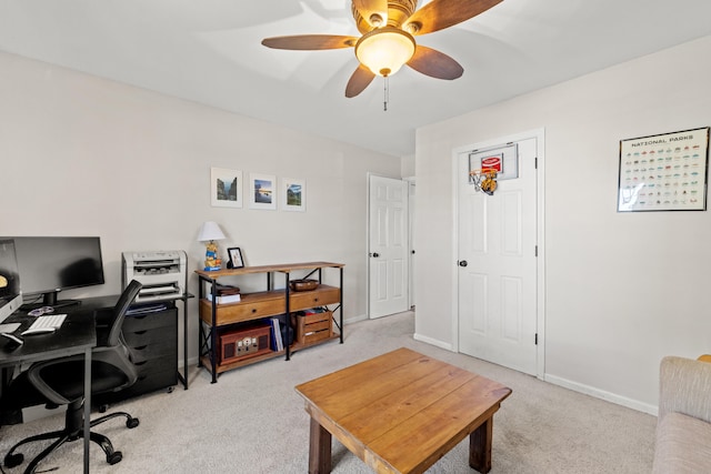 office space featuring baseboards, a ceiling fan, and light carpet