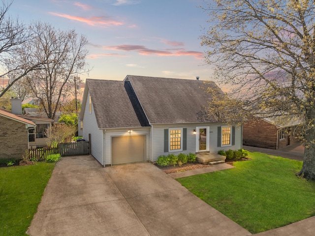 new england style home featuring a lawn, a garage, fence, concrete driveway, and a shingled roof