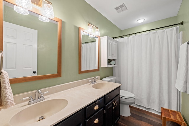 full bathroom with a sink, toilet, wood finished floors, and visible vents