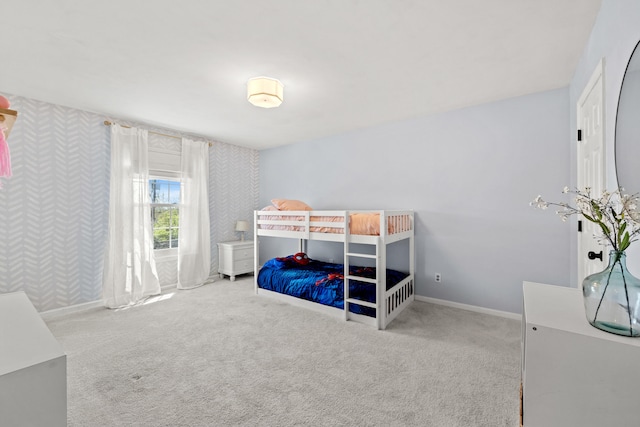carpeted bedroom featuring wallpapered walls and baseboards