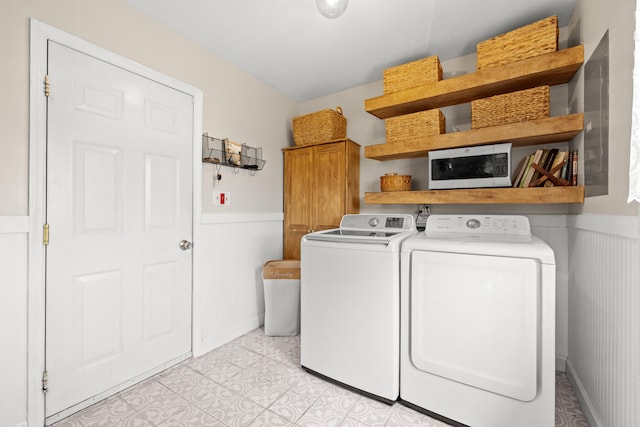 clothes washing area with independent washer and dryer, cabinet space, and a wainscoted wall