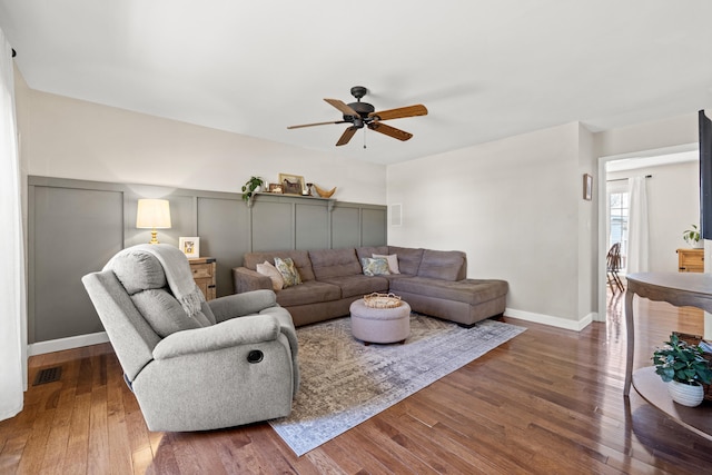 living area featuring baseboards, wood-type flooring, a ceiling fan, and visible vents