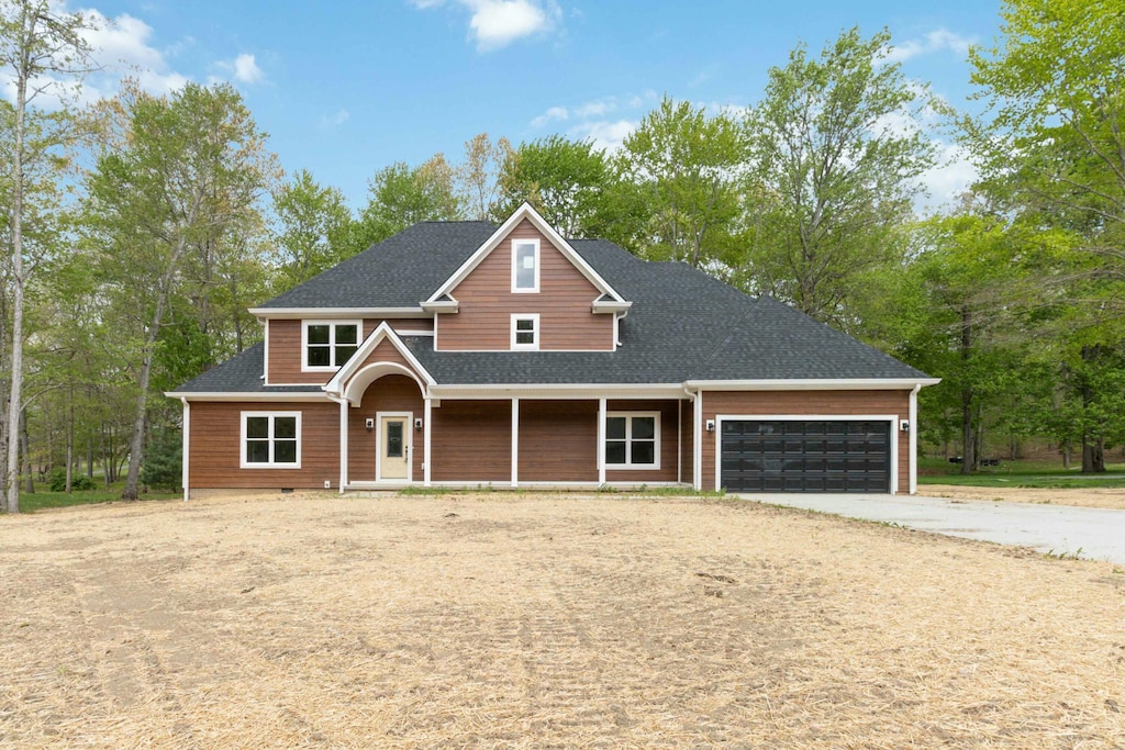 craftsman-style home featuring concrete driveway, an attached garage, covered porch, and roof with shingles