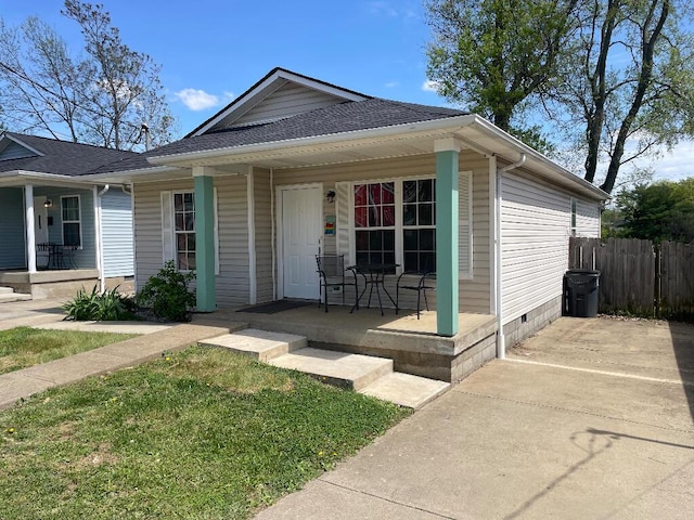 view of front facade featuring fence, a porch, roof with shingles, and crawl space