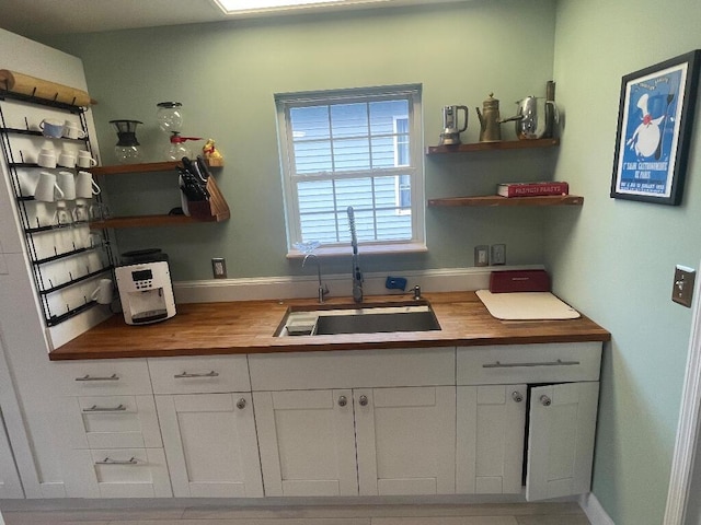 kitchen featuring a sink, butcher block countertops, open shelves, and white cabinetry