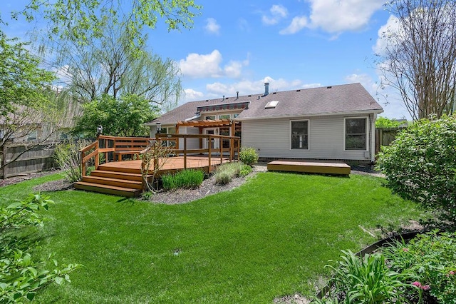 rear view of house with a fenced backyard, a wooden deck, a yard, and roof with shingles