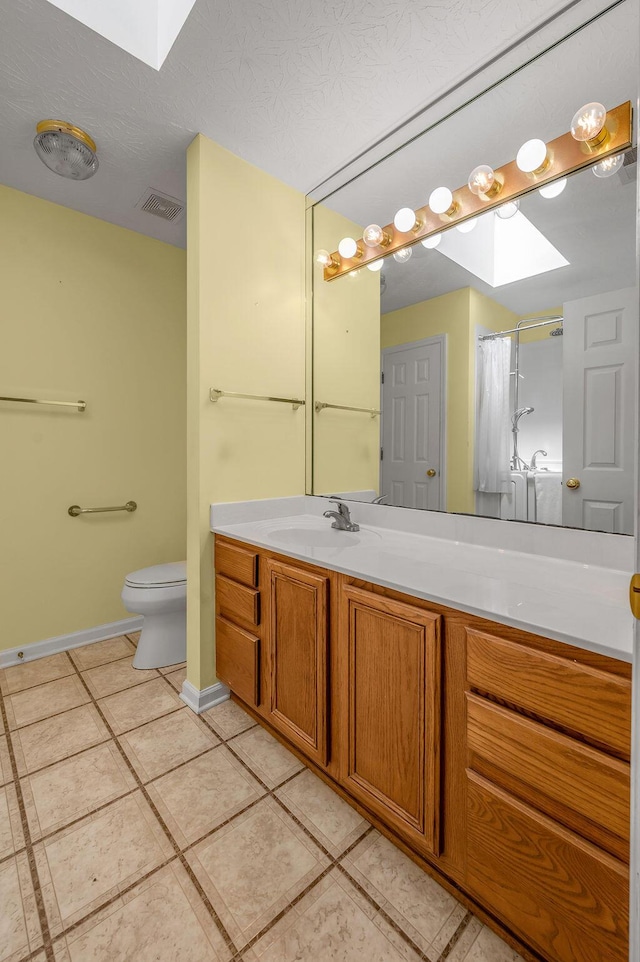 full bath featuring vanity, tile patterned floors, toilet, visible vents, and a skylight