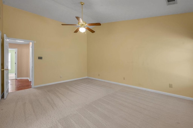spare room with a ceiling fan, visible vents, light carpet, and baseboards