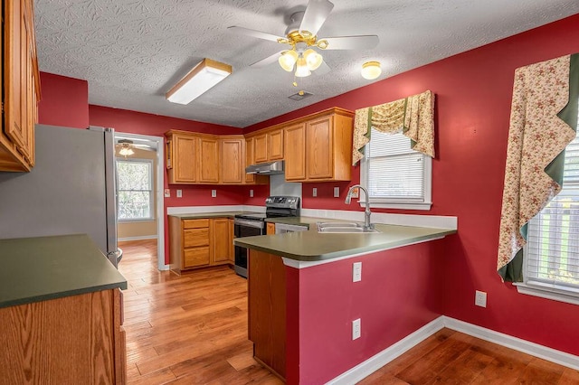 kitchen with a sink, appliances with stainless steel finishes, ceiling fan, under cabinet range hood, and a peninsula
