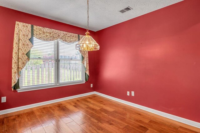 unfurnished dining area with wood finished floors, visible vents, a healthy amount of sunlight, and baseboards
