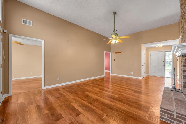 interior space featuring visible vents, baseboards, light wood finished floors, a towering ceiling, and a ceiling fan