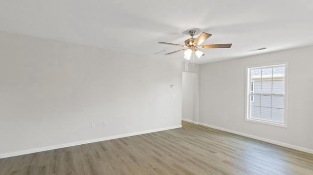 unfurnished room featuring baseboards, visible vents, wood finished floors, and ceiling fan