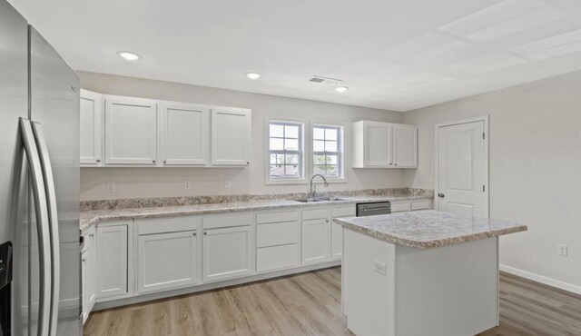 kitchen with a sink, light wood-style flooring, a kitchen island, white cabinetry, and appliances with stainless steel finishes