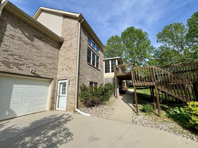 view of property exterior with a deck, brick siding, driveway, and stairs