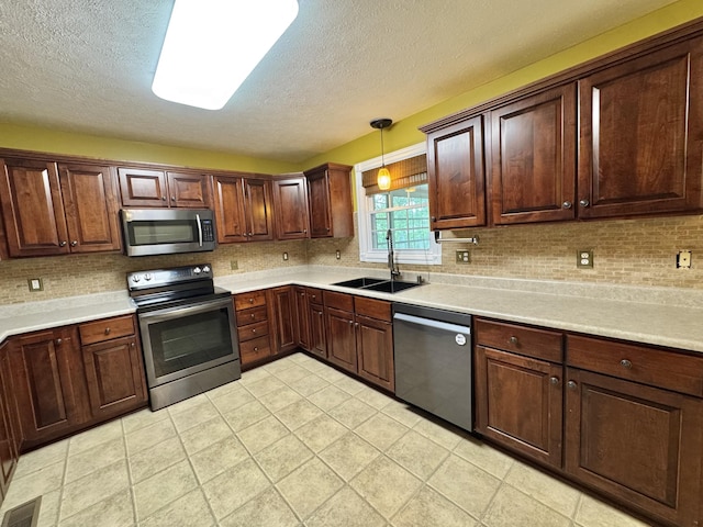 kitchen featuring appliances with stainless steel finishes, a textured ceiling, visible vents, and a sink