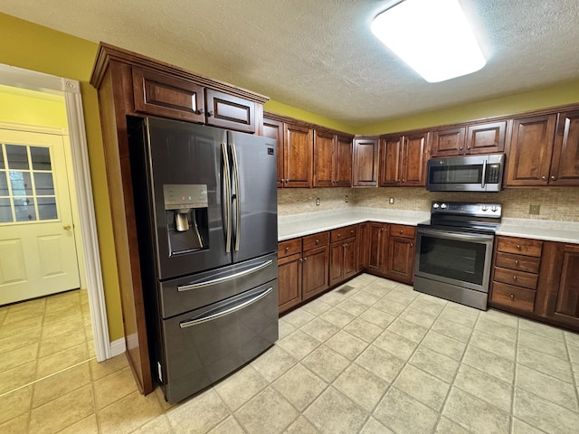 kitchen featuring a textured ceiling, backsplash, stainless steel appliances, and light countertops