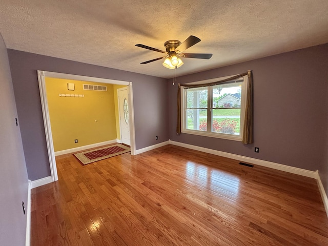 unfurnished room featuring a textured ceiling, visible vents, and wood finished floors
