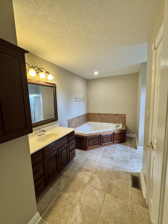 bathroom featuring a bath, a textured ceiling, visible vents, and vanity