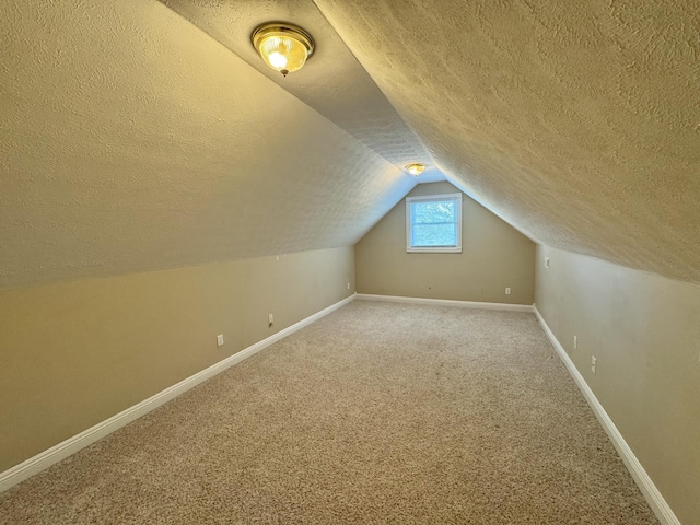 additional living space with lofted ceiling, a textured ceiling, and carpet flooring