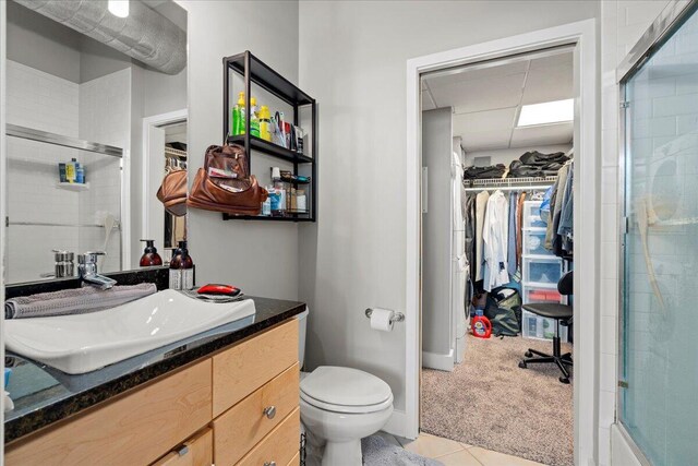 121 N Martin Luther King Blvd Unit 401, Lexington, KY 40508 - bathroom with a tile shower, vanity, toilet, a spacious closet, and tile patterned flooring
