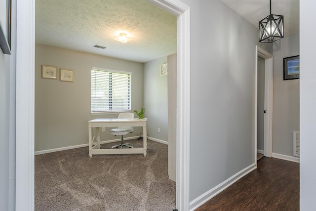 hall with baseboards, visible vents, and a textured ceiling