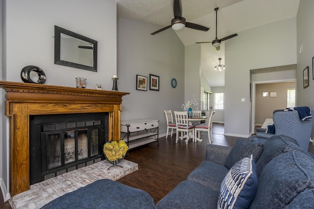 living room featuring ceiling fan, baseboards, a glass covered fireplace, wood finished floors, and high vaulted ceiling