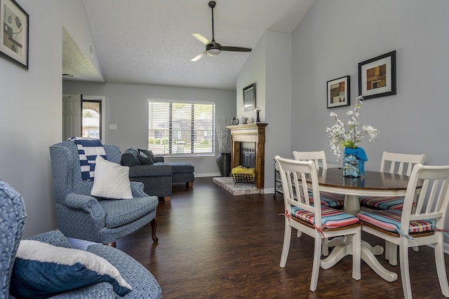interior space featuring a glass covered fireplace, wood finished floors, ceiling fan, and baseboards